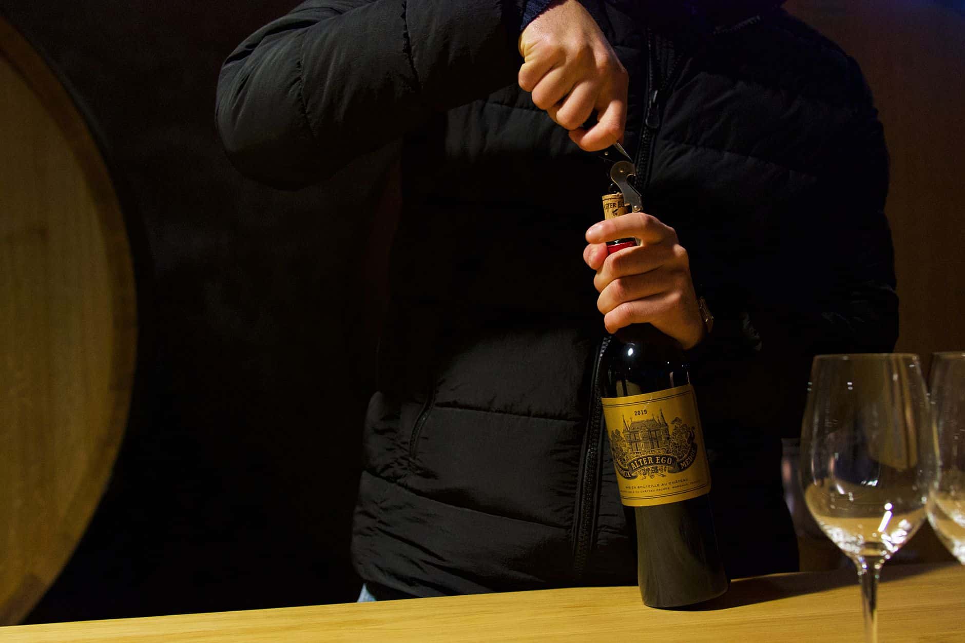 Dégustation de vin dans un chai bordelais avec des fûts de chêne en arrière-plan