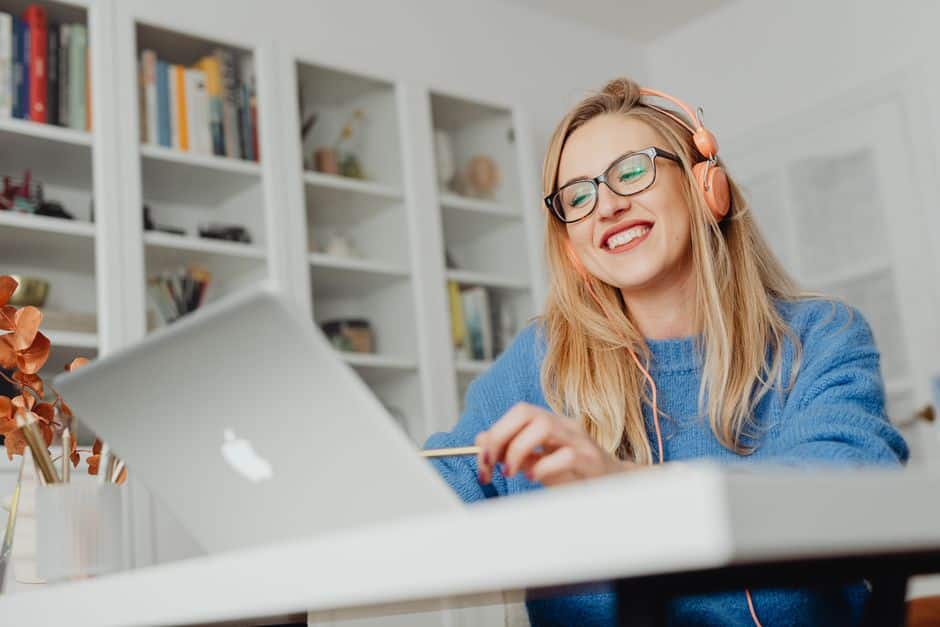 Femme souriante avec un casque suivant un cours en ligne sur son ordinateur portable