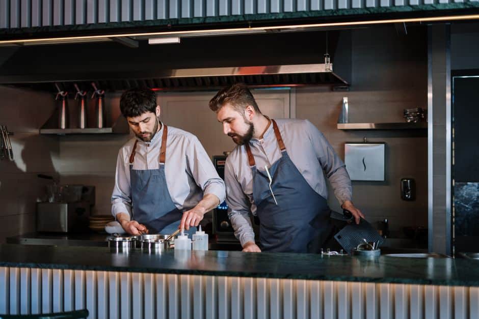 Deux cuisiniers en tablier travaillant dans une cuisine ouverte moderne