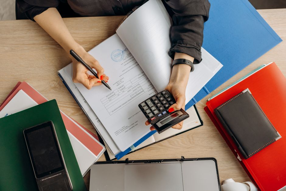 Comptable analysant des documents financiers avec une calculatrice sur un bureau
